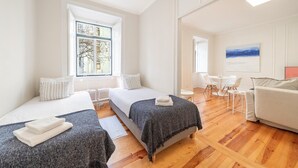 A hotel room with two beds, a dining area, and a view of the outdoors. - GuestReady - Castle - Apt for 4 guests in Saldanha (Lisboa)