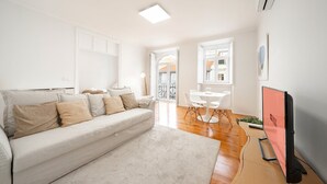 Un salon avec un canapé, une table à manger et des chaises, un téléviseur et une fenêtre.