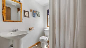 Une salle de bain avec un lavabo blanc, des toilettes et un miroir encadré en bois.