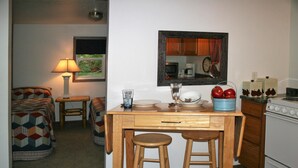 Una cocina compacta con una mesa de madera, dos taburetes, un microondas y una estufa.