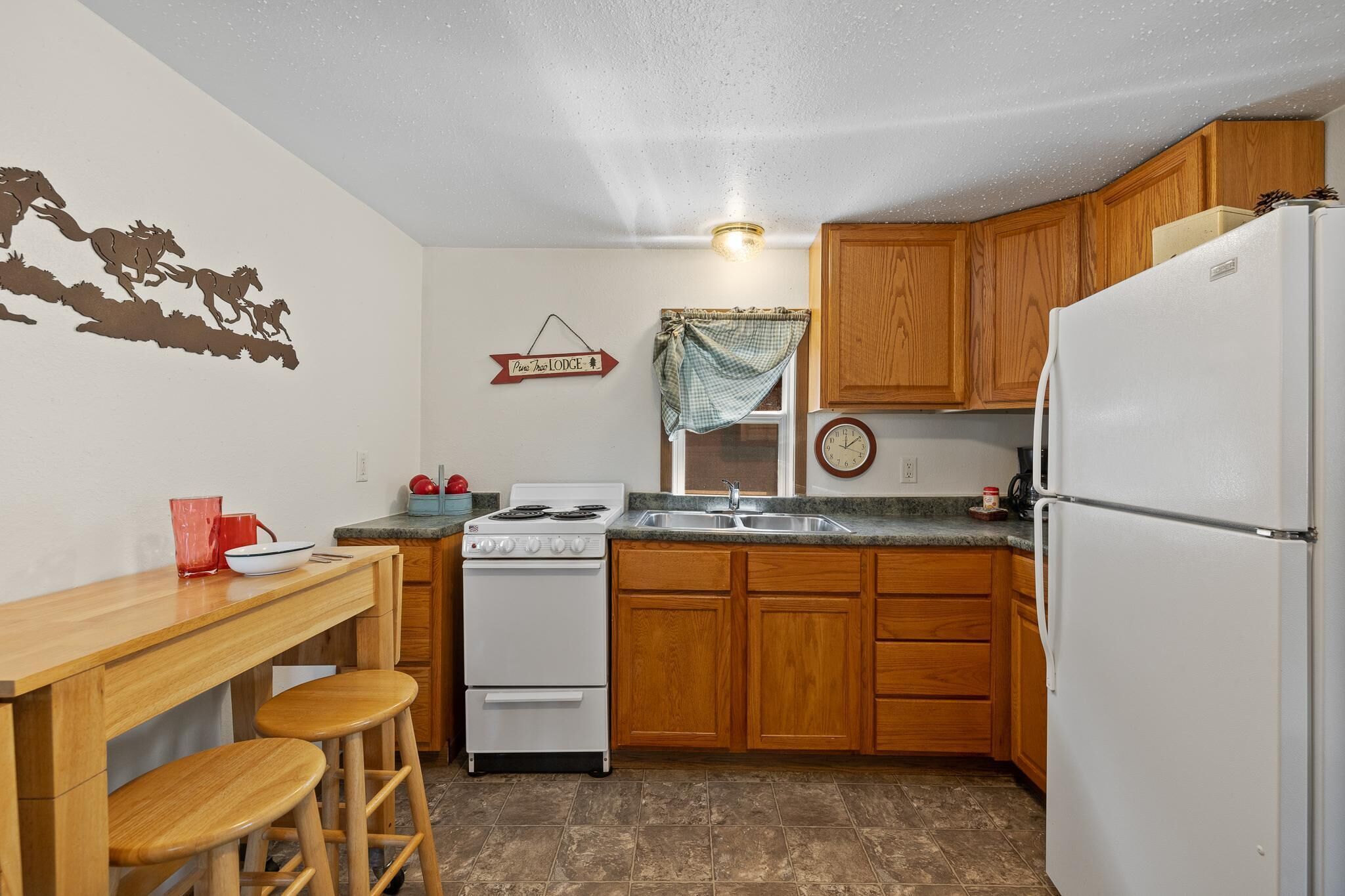 Une cuisine de taille réduite, avec des meubles de rangement en bois, une cuisinière blanche et un réfrigérateur.