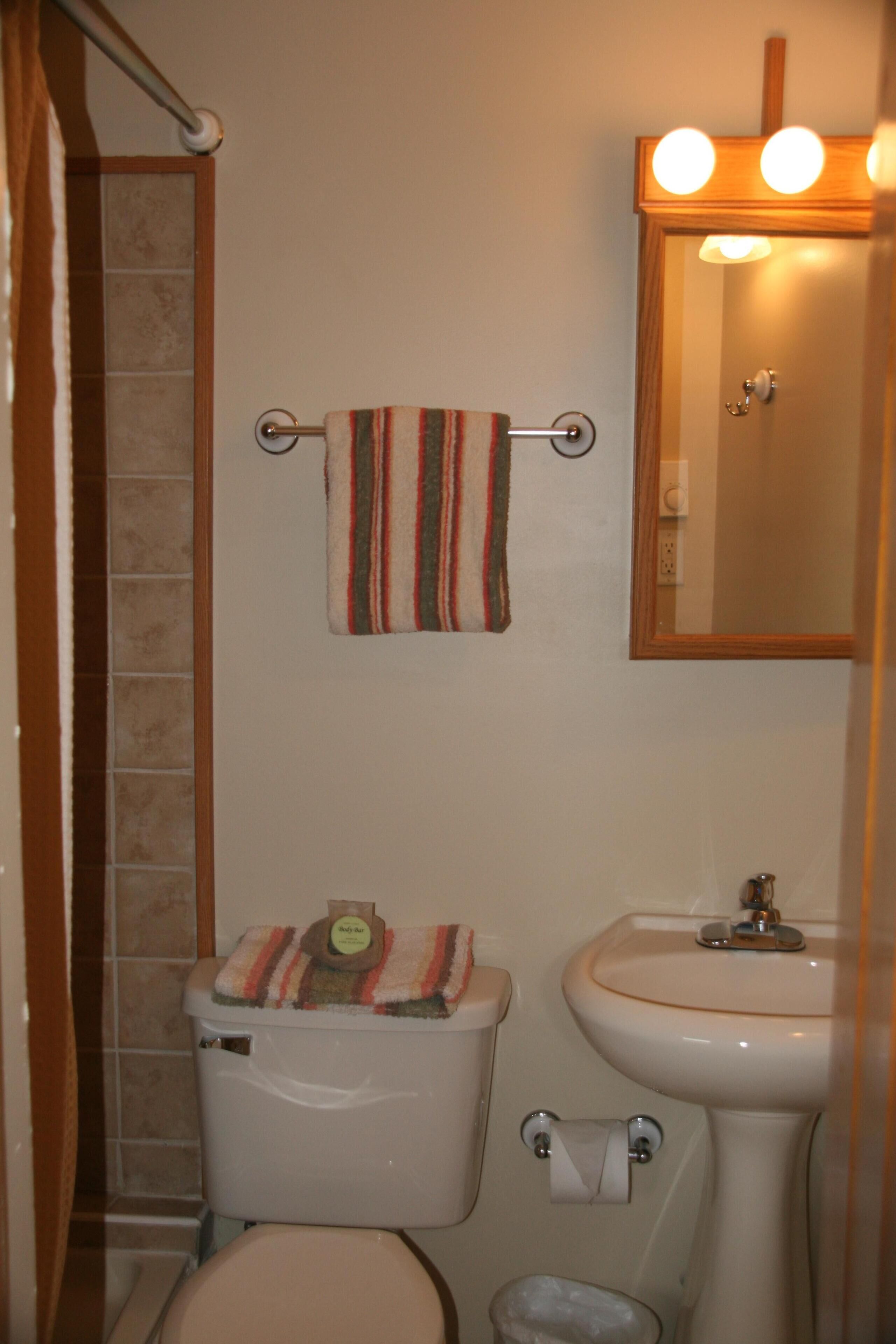 Ein Badezimmer mit Toilette, Waschbecken und einem Handtuchhalter mit gestreiftem Handtuch.