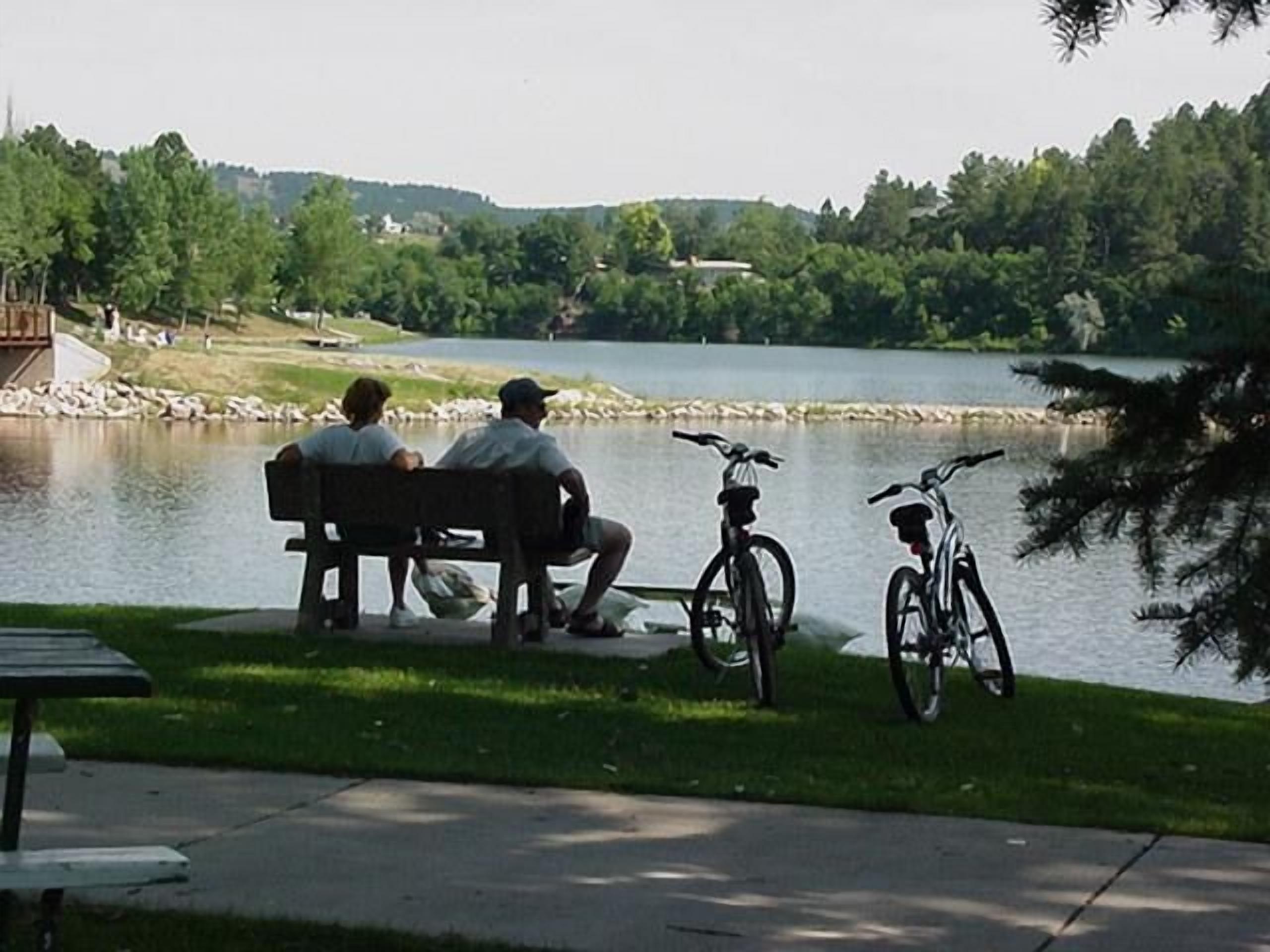 Un banco junto a un lago, con bicicletas aparcadas cerca.