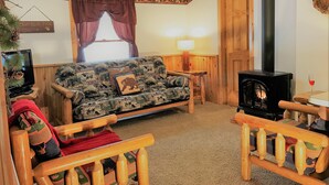 Ein gemütliches Wohnzimmer mit einer Couch, einem Holzstuhl, einem Kamin und einer Lampe.