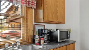 A kitchen with wooden cabinets, a stainless steel sink, a coffee maker, and a microwave.