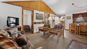 A cozy living room with a television, a sofa, a wooden dining table with chairs, and a staircase leading to another level. - Make Memories from your Deck - In Rapid City On Canyon Lake Thirty Minutes from Mt Rushmore (Rapid City)