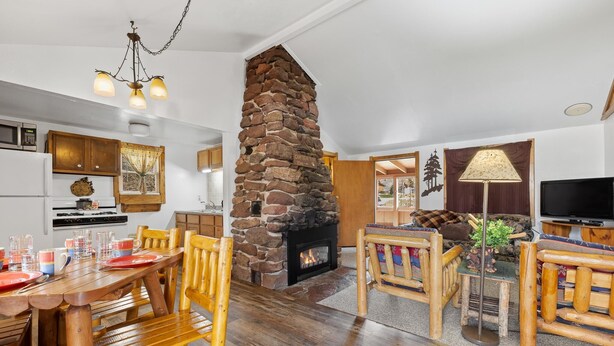 A cozy living area with a stone fireplace, wooden furniture, and a television. - Make Memories from your Deck - In Rapid City On Canyon Lake Thirty Minutes from Mt Rushmore (Rapid City)