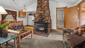 A cozy living room with a stone fireplace, wooden furniture, and a dining area. - Make Memories from your Deck - In Rapid City On Canyon Lake Thirty Minutes from Mt Rushmore (Rapid City)