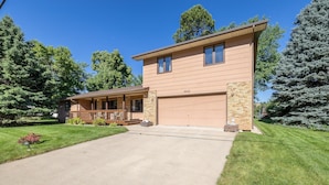 A two-story house with a garage, a covered porch, and a well-maintained lawn. - Cougar Lodge Vacation Home Thirty Minutes from Mt Rushmore - In Rapid City On Canyon Lake Thirty Minutes from Mt Rushmore (Rapid City)