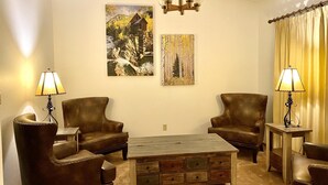 A cozy living room with two leather armchairs, a wooden coffee table, and two lamps. There are two paintings on the wall. - Cougar Lodge Vacation Home Thirty Minutes from Mt Rushmore - In Rapid City On Canyon Lake Thirty Minutes from Mt Rushmore (Rapid City)