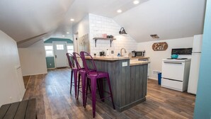A modern kitchen with a central island, bar stools, and a microwave. - Percival`s Perch at The Judge Jones Historic Homes (Flagstaff)