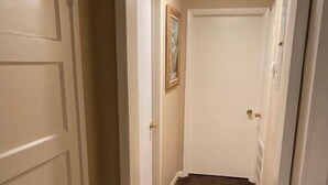 Um corredor estreito com pisos cobertos de carpete e portas brancas.