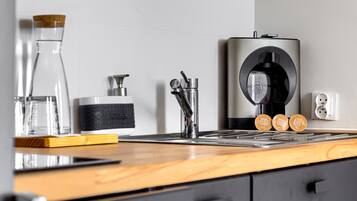 A kitchen with a coffee machine, a coffee grinder, and a coffee maker.
