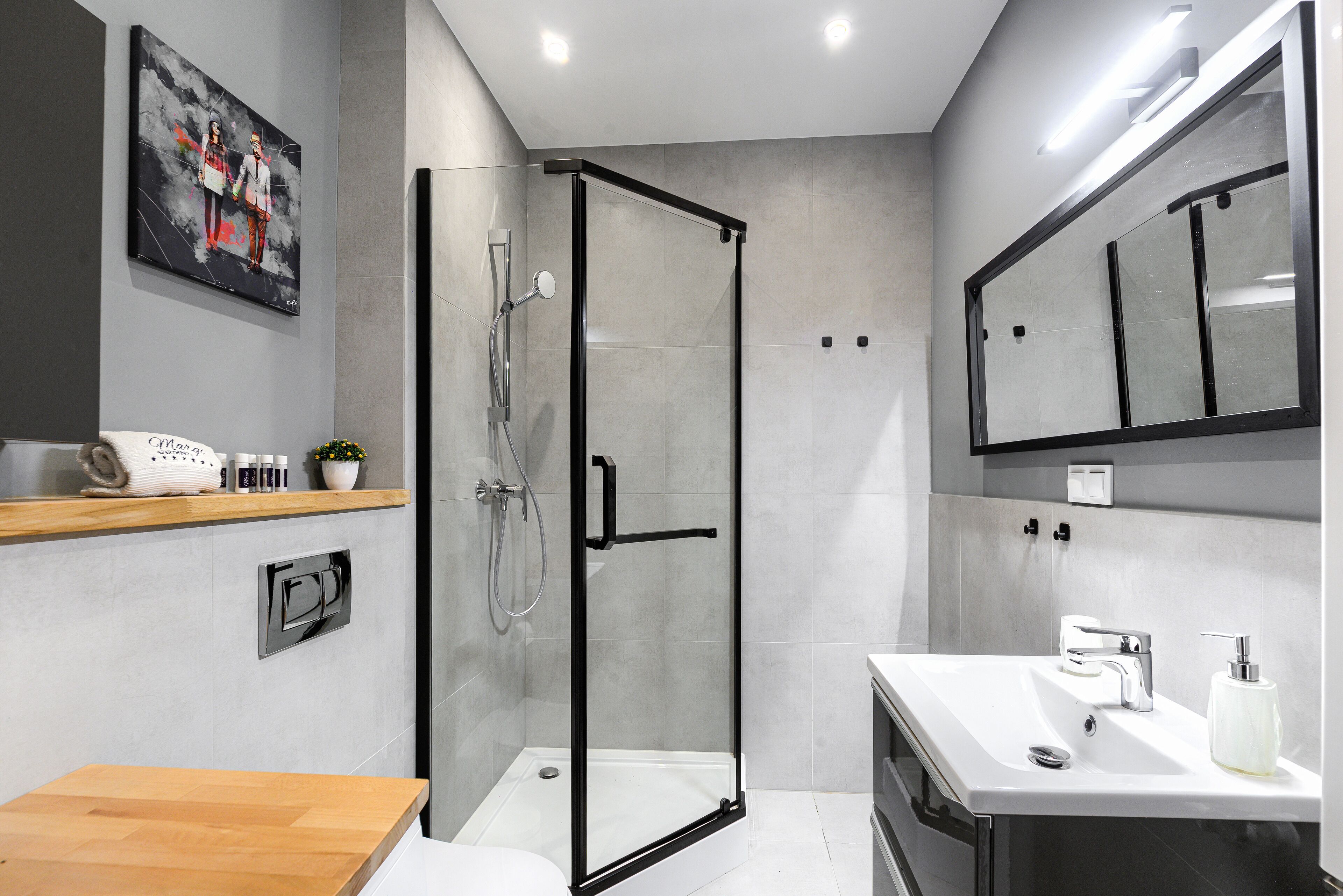 Un baño moderno con cabina de ducha de vidrio, tocador de madera y un espejo grande.