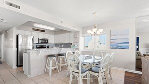A modern kitchen with white cabinetry, stainless steel appliances, and a central island with bar stools. - Charming oceanfront resort w/indoor & outdoor pools, lazy river, kids pools-perfect for family trips (North Myrtle Beach)
