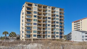 Un hotel de varios pisos con balcones, situado cerca de una playa de arena.