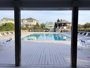 Un espace piscine doté d’une terrasse en bois, de chaises longues et offrant une vue sur les bâtiments environnants.