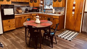 Una cocina con armarios de madera, estufa y una mesa de comedor con sillas.