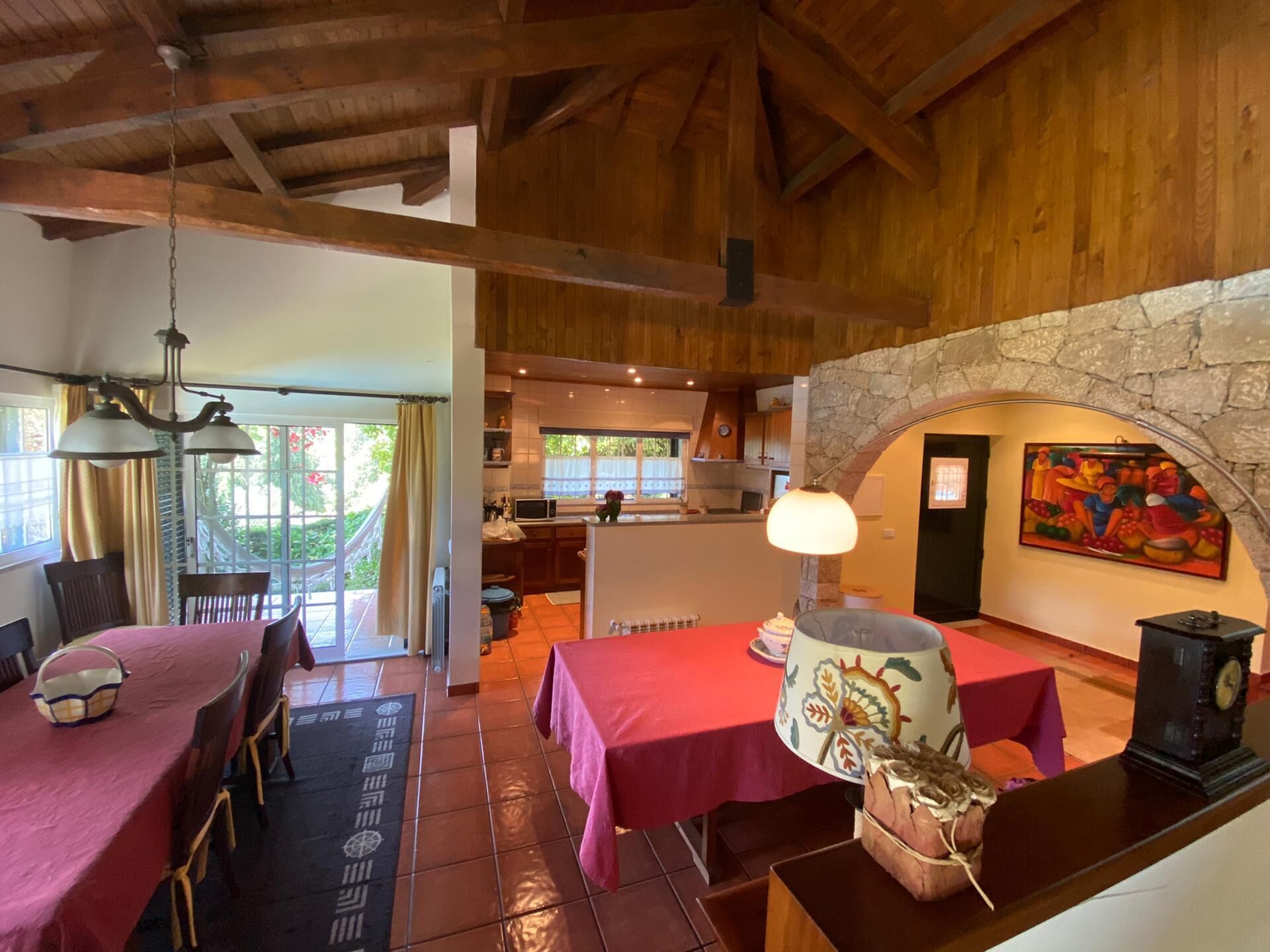 A dining area with red tablecloths, wooden beams, and a stone wall.