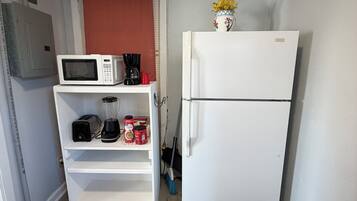Una kitchenette funcional con microondas, cafetera, tostadora y refrigerador.
