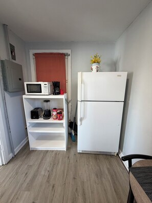 A compact kitchenette with a microwave, coffee maker, toaster, and a refrigerator. - Historic Cozy Apartment near Hospital & VSU -SF (Valdosta)