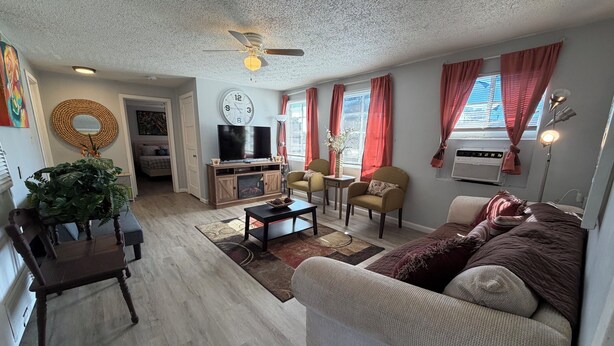 Un salon comprenant un canapé, des fauteuils, une table basse, un téléviseur et un ventilateur de plafond.