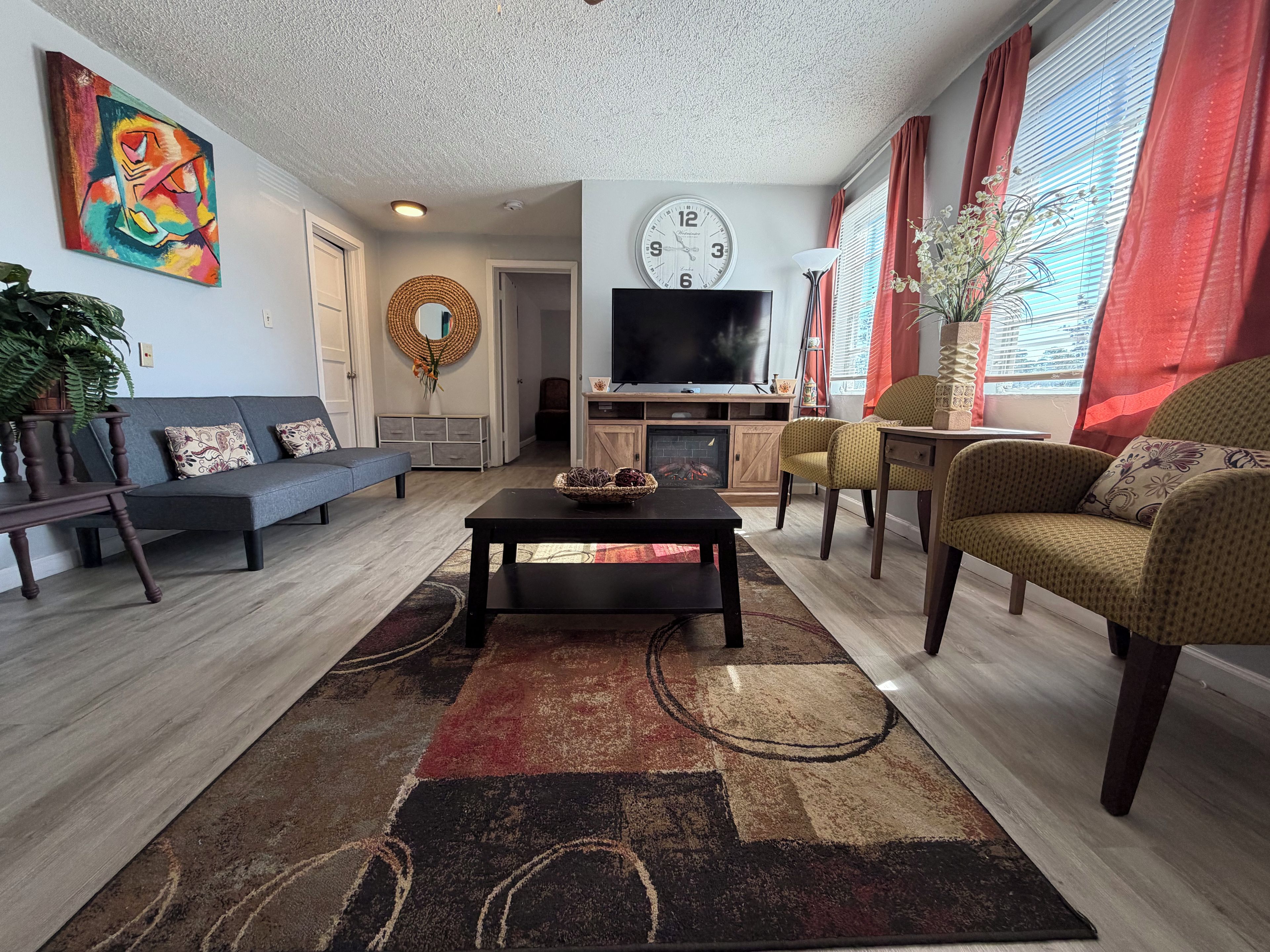 A living room with a sofa, armchairs, a coffee table, a TV, and a fireplace.