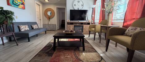 A living room with a sofa, armchairs, a coffee table, a TV, and a fireplace.