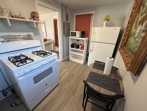Una cocina compacta con estufa a gas, microondas y refrigerador.