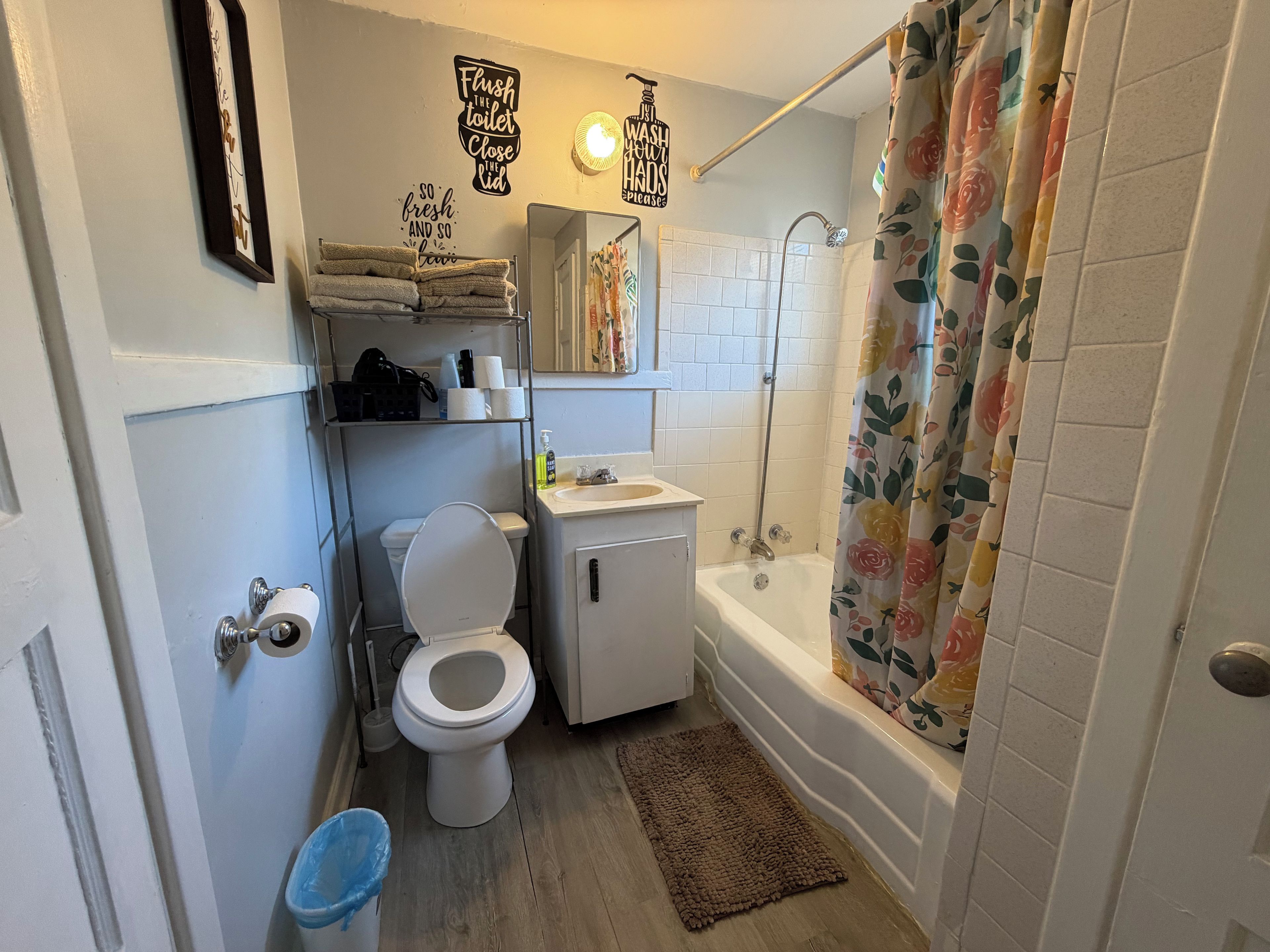 A bathroom with a toilet, sink, shower, and a towel rack.