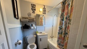 Une salle de bain comprenant des toilettes, un lavabo, une douche et un porte-serviettes.