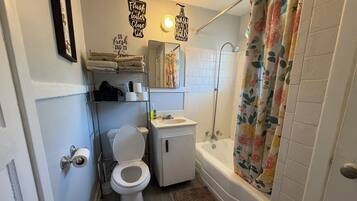 A bathroom with a toilet, sink, shower, and a towel rack.