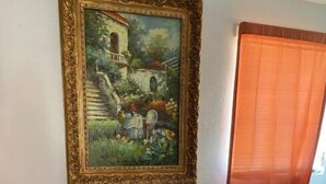 Ein Essbereich mit Tisch und Stühlen, einem Bild an der Wand und einem Fenster mit Vorhängen.