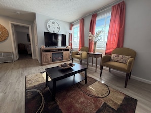 Una sala de estar con chimenea, televisor y dos sillones.