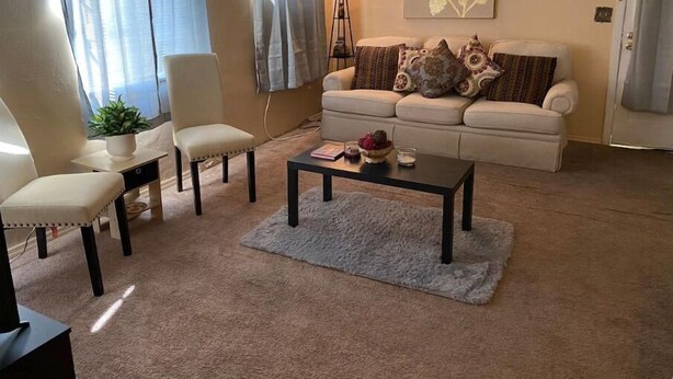 Un salon comprenant un canapé, deux fauteuils, une table basse, un lampadaire et un tableau accroché au mur.