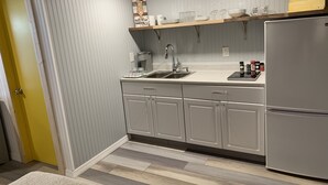 A kitchen with grey cabinets, a stainless steel sink, and a refrigerator. - Happy Hour ACROSS THE STREET FROM THE BEACH (Treasure Island)
