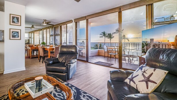 A spacious living area with a balcony, leather furniture, and a dining setup.