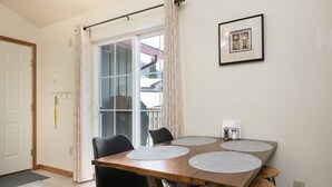 Een eetgedeelte met een houten tafel, vier stoelen en een groot raam met gordijnen.
