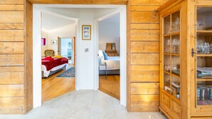 A wooden interior with a bed, a cabinet with glass doors, and a hallway leading to another room.