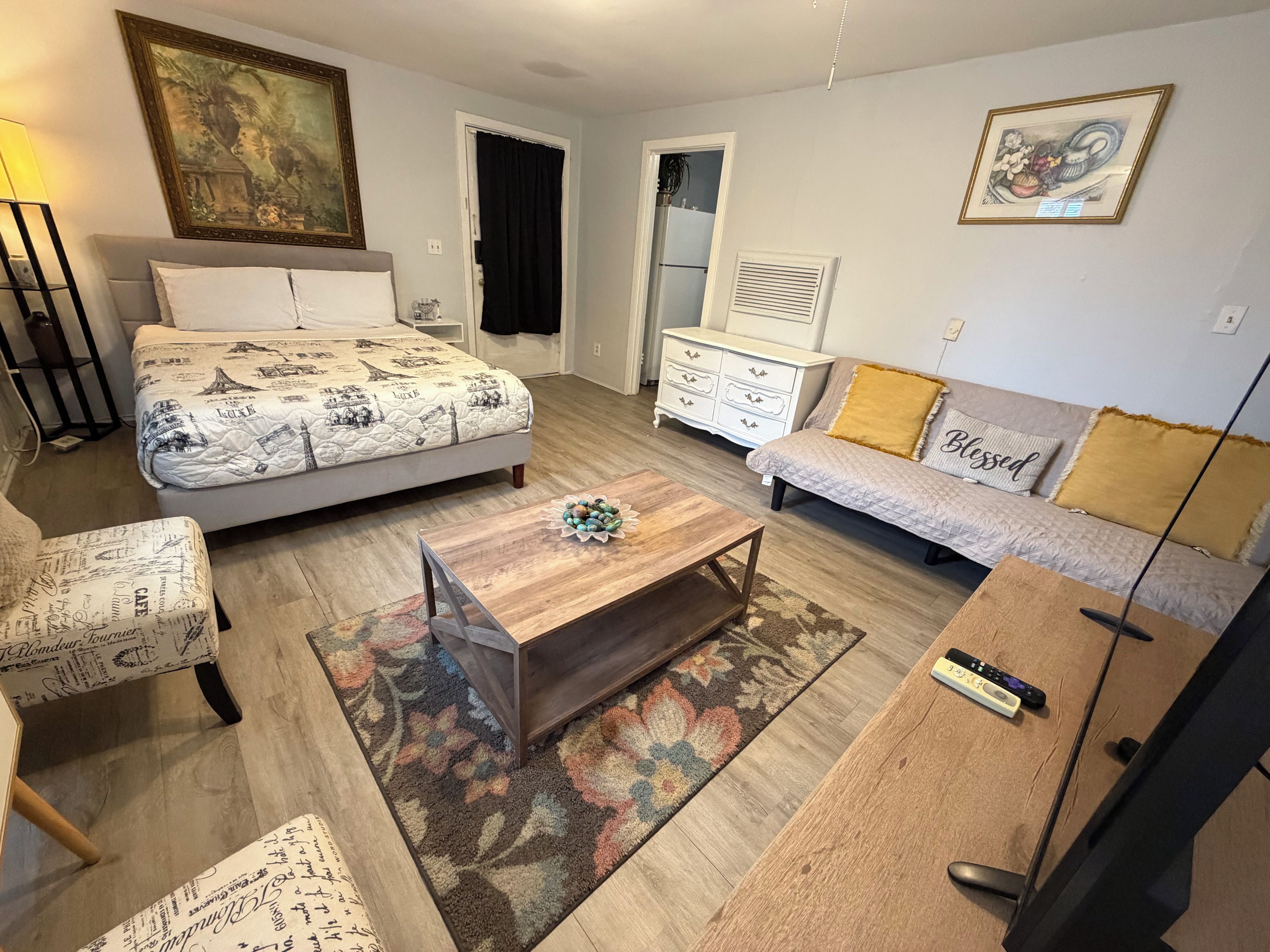 A furnished living room with a bed, sofa, coffee table, and a TV.