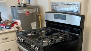 Uma cozinha com fogão preto, forno de aço inoxidável e geladeira.