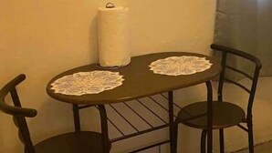 Uma pequena mesa de jantar com duas cadeiras, uma vela e uma toalha rendada.