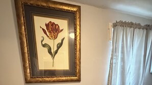 Un comedor con una mesa y sillas, un cuadro en la pared y una ventana con cortinas.