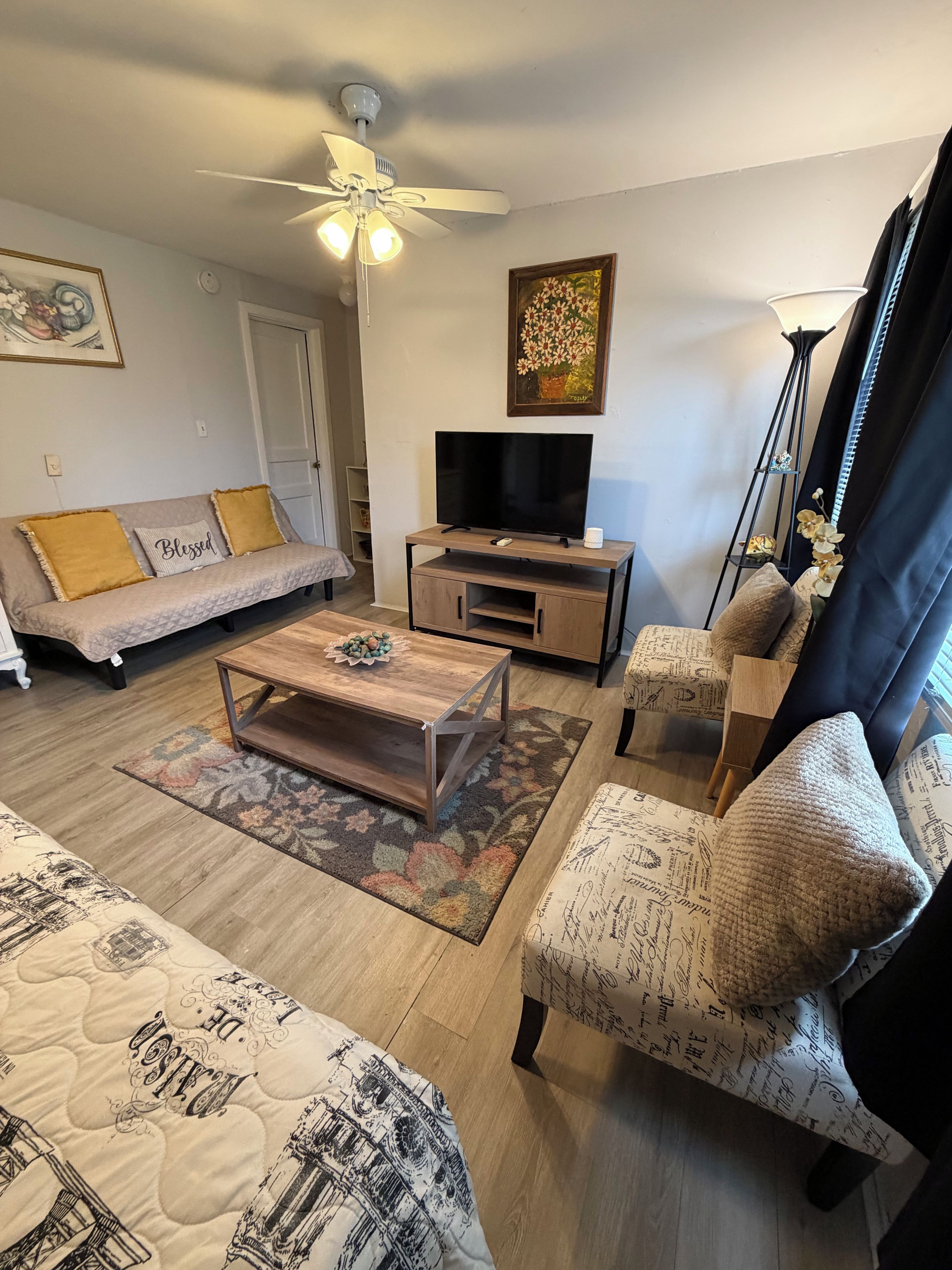 A living room with a sofa, a coffee table, a TV, and a chair with a patterned cushion.