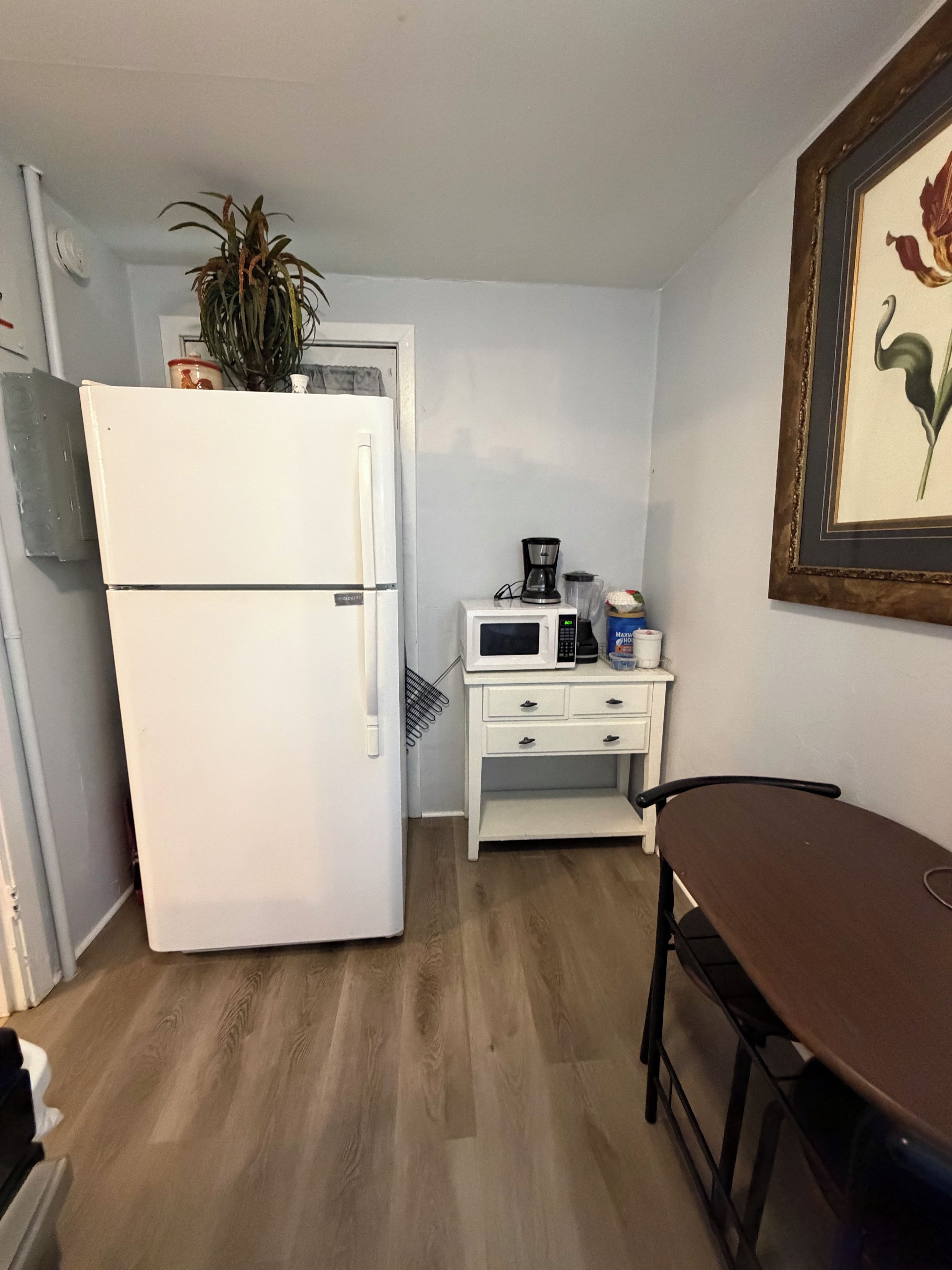 Una cocina compacta equipada con refrigerador, microondas, cafetera y una pequeña mesa.