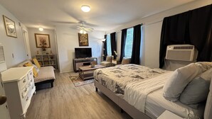 Un dormitorio moderno con cama, mesita de noche, cómoda, televisor y ventilador de techo.