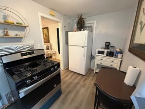 A compact kitchen with a stove, refrigerator, microwave, and a small dining area. - Valdosta Studio Near VSU & SGMC  Long Stays (Valdosta)