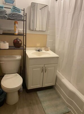 Bañera con ducha, toallas, jabón, papel higiénico