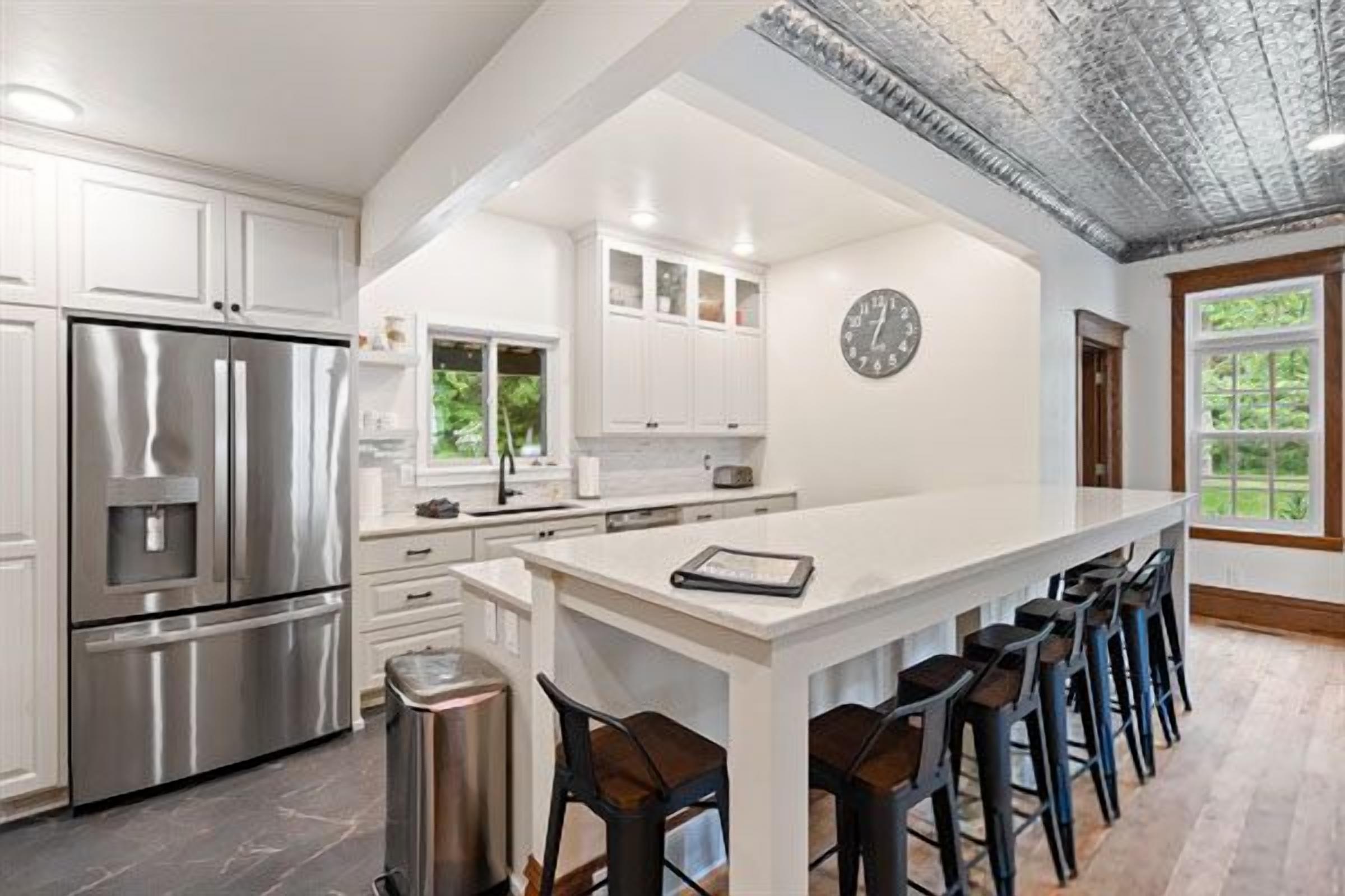 A modern kitchen with stainless steel appliances, a white island, and bar stools.