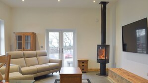 A living room with a sofa, a coffee table, a TV, a fireplace, and a cabinet. - 2 bedroom accommodation in Glandwr, near Narbeth (Glandwr, near Narbeth)